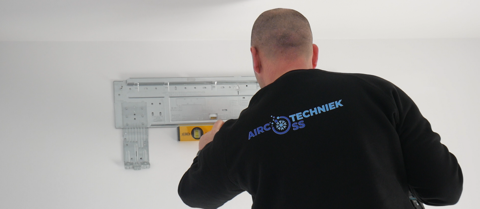 Monteur van Airco Techniek Oss plaatst een binnenunit aan de wand